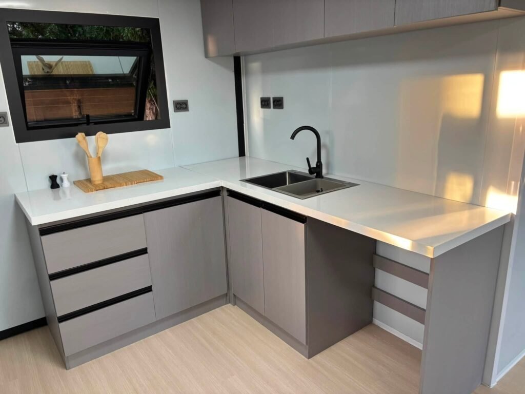 Cuisine équipée d'une maison Otini : plan de travail blanc, évier double et rangements