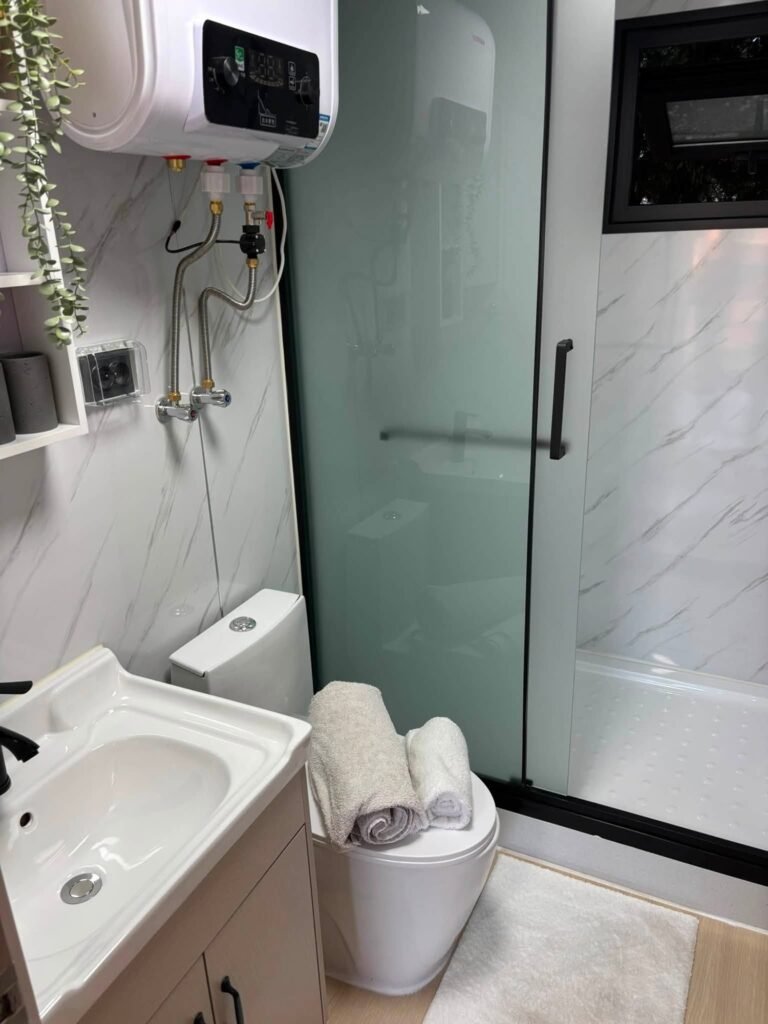 Salle d'eau d'une maison Otini : douche, WC, lavabo et chauffe-eau