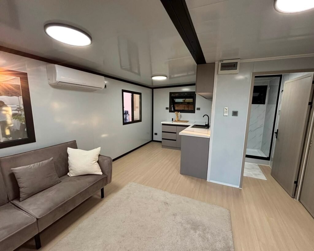 Séjour d'une maison Otini au showroom, avec la cuisine et la salle d'eau au fond